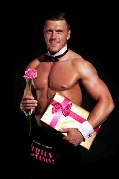 Butler posing for a photo whilst holding a pink rose and box of chocolates