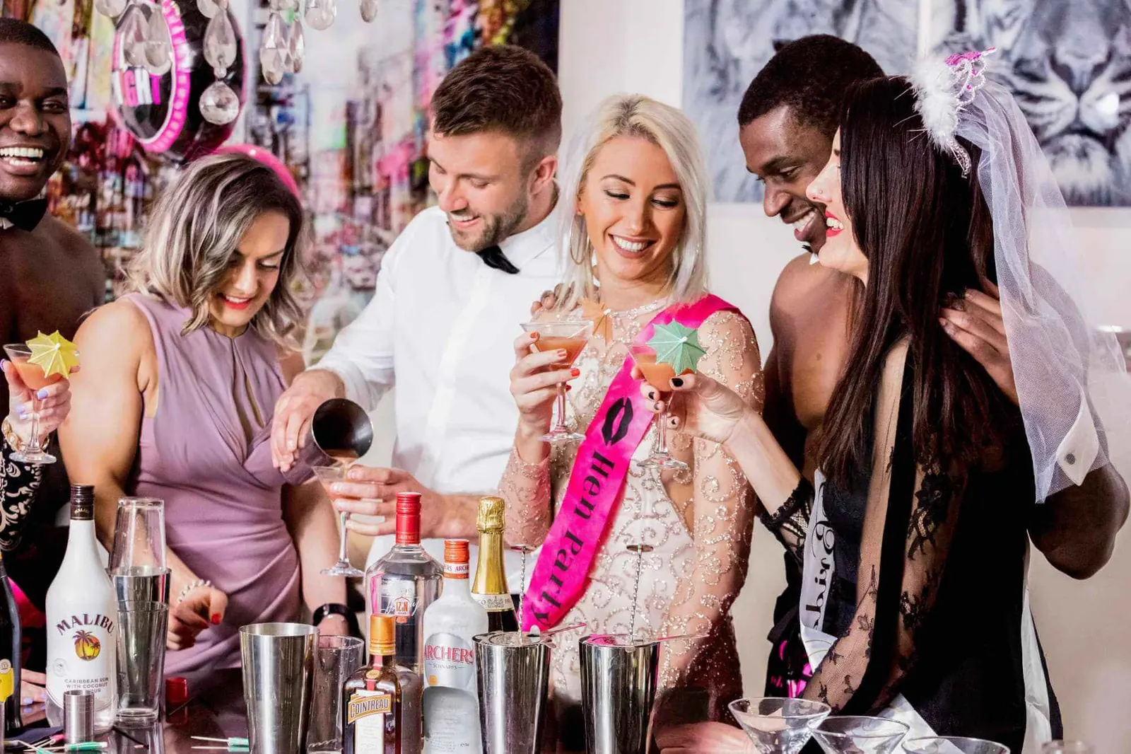Butler pouring drinks for hens wearing sashes at a hen party