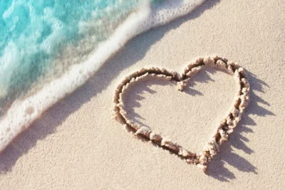 A heart drawn in the sand at the edge of a turquoise sea