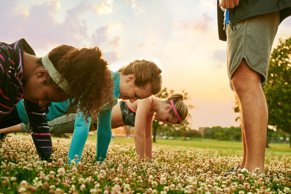 Three girls doing pushups outside for a boot camp